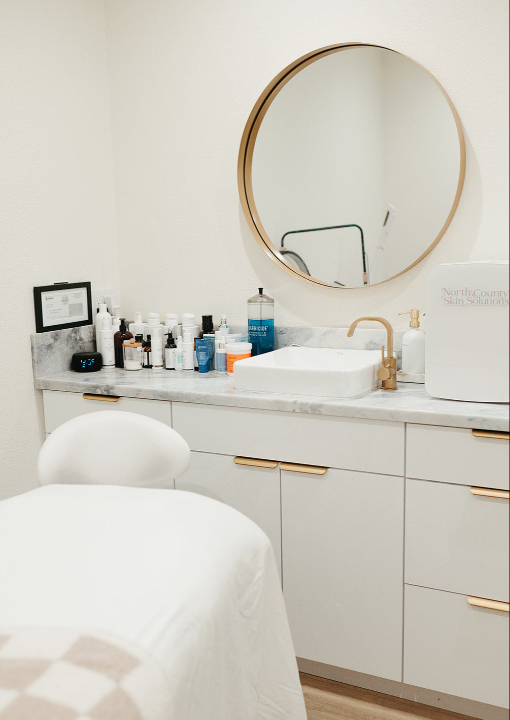 Bathroom vanity with round mirror, sink, and various toiletries.