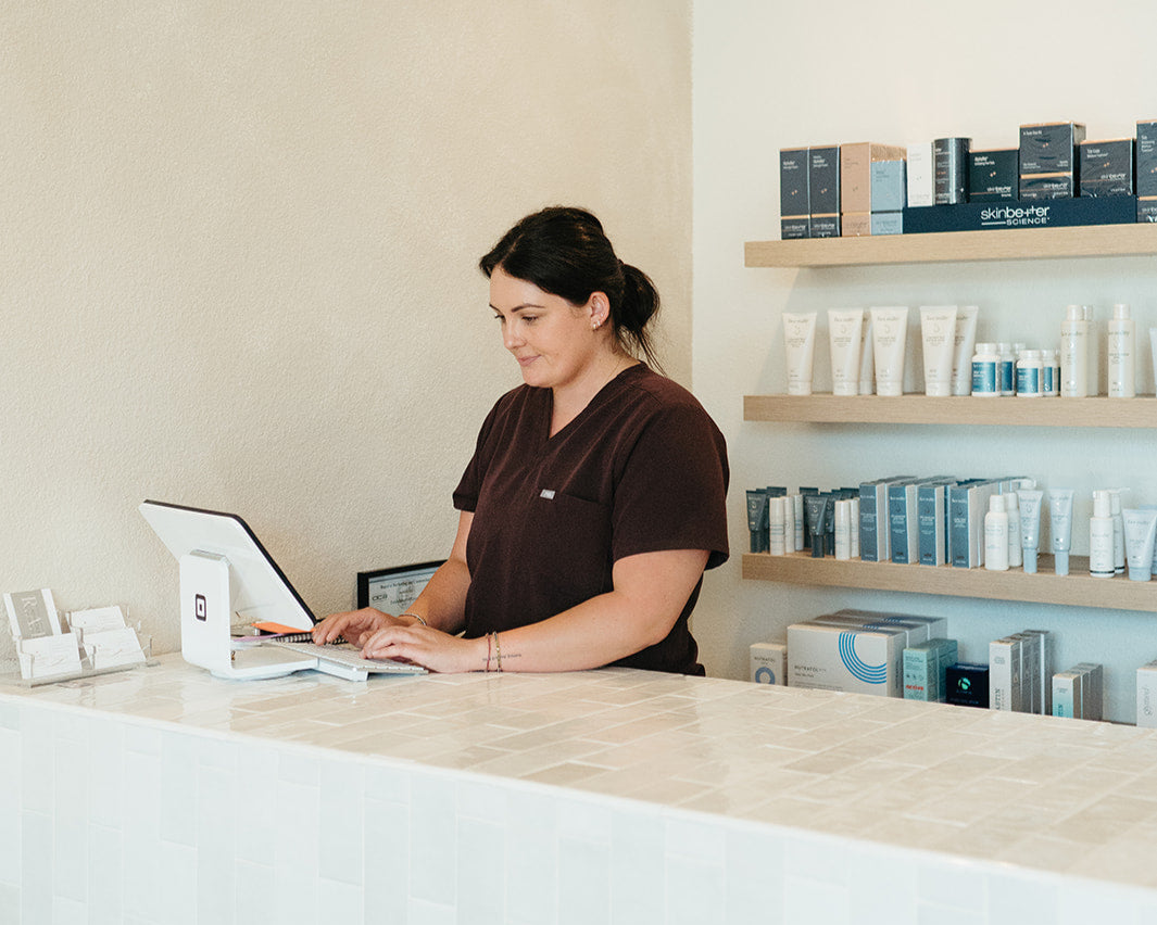 Person working on a laptop at a counter in a store setting.