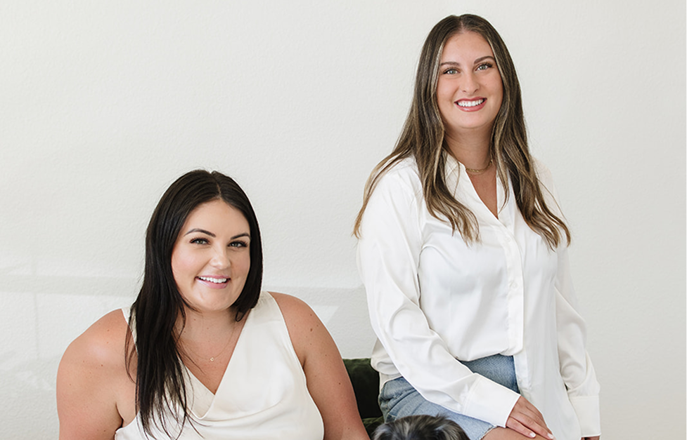 Two women sitting side by side against a white background