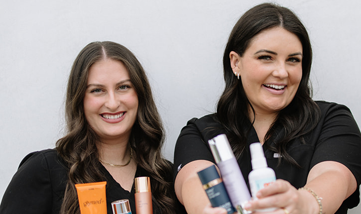 Two women holding skincare products against a plain background
