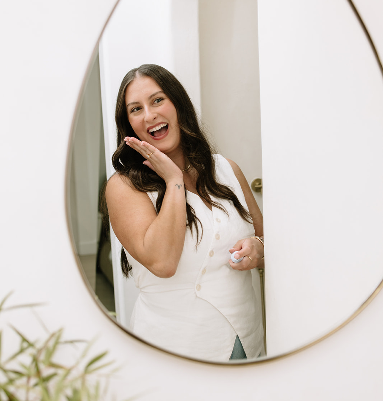 Woman in a white dress standing in front of a mirror